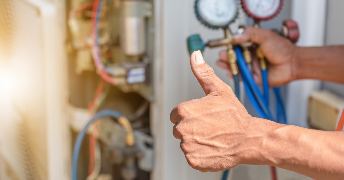 A person giving a thumbs-up while checking an HVAC unit.