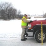 Man looks at building plans in truck in snow.