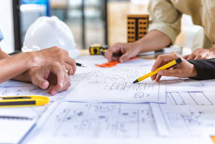 Three men look over building plans.