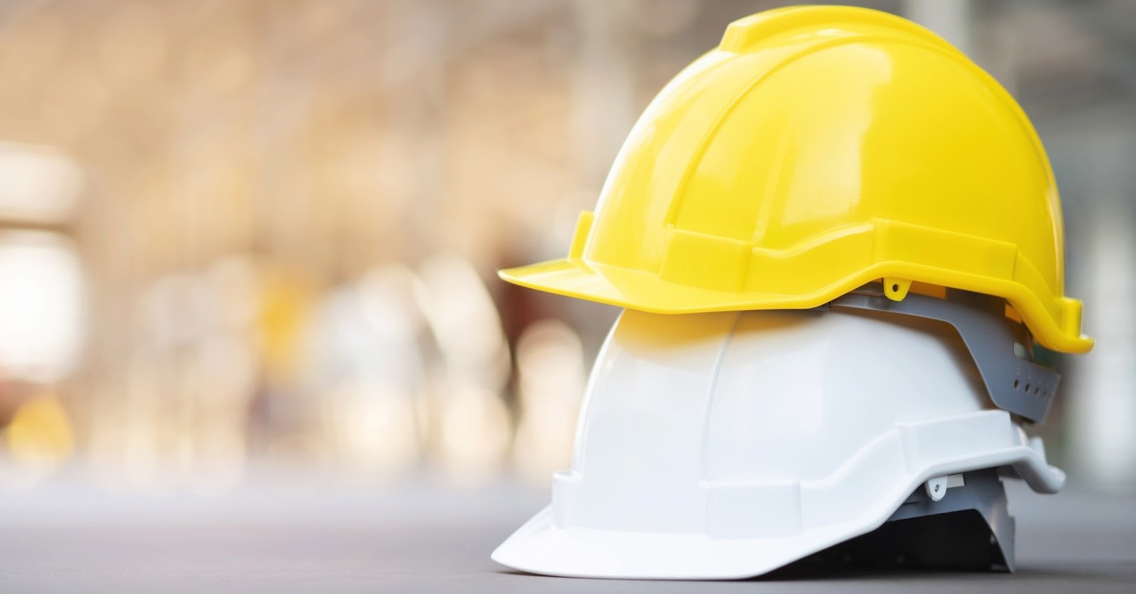 A yellow hard hat stacked on top of a white hard hat.