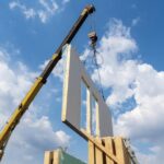 A crane lifting the wall of a modular building during construction.