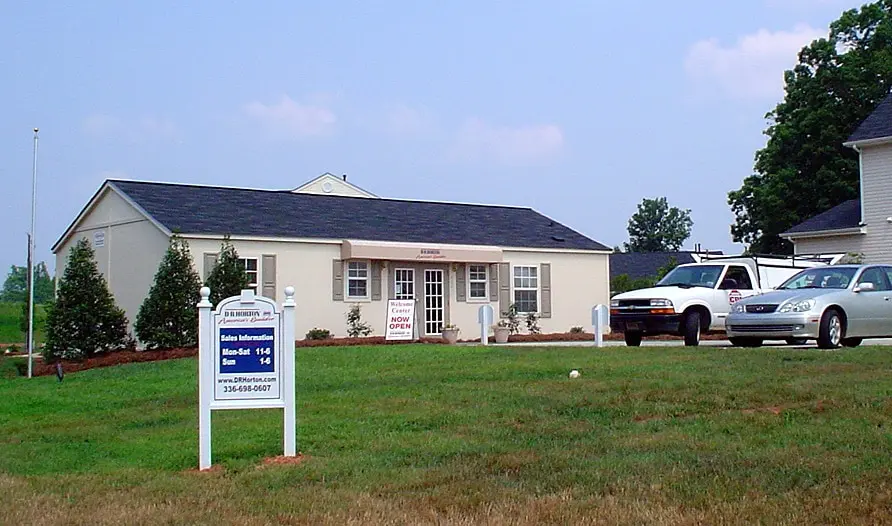 exterior of modular building with pitched roof and two cars in parking lot