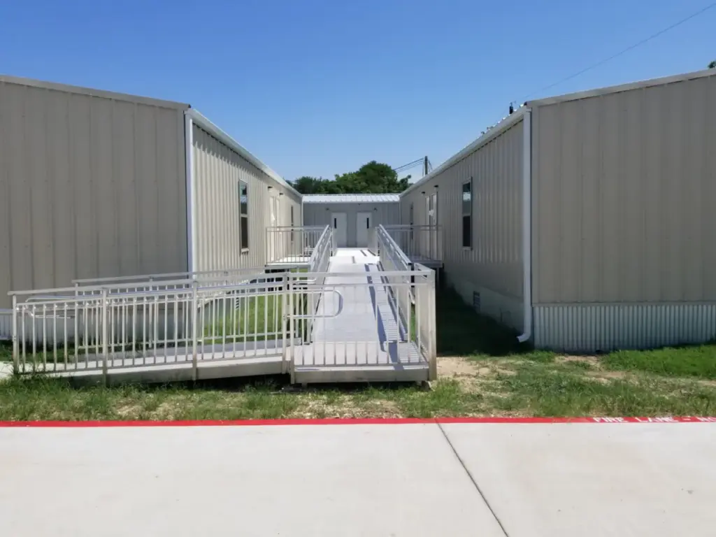 exterior of steel sided modular classrooms with aluminum access ramp between buildings