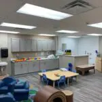 interior of modular educational toddler classroom with cabinets tables and chairs