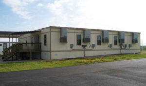 Exterior of a s-plex modular building with 4 buildings, HVAC units, stairs leading to an exterior door. 