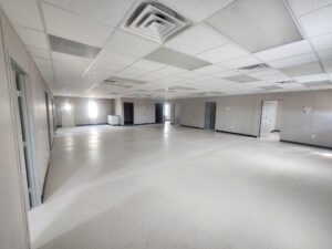 Interior of a s-plex modular building with private offices, a large open meeting space, and cabinets with a sink. 