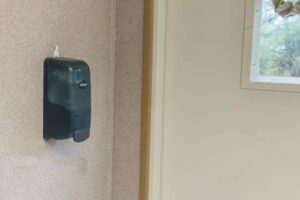 Hand sanitizing station attached to the wall of a mobile office