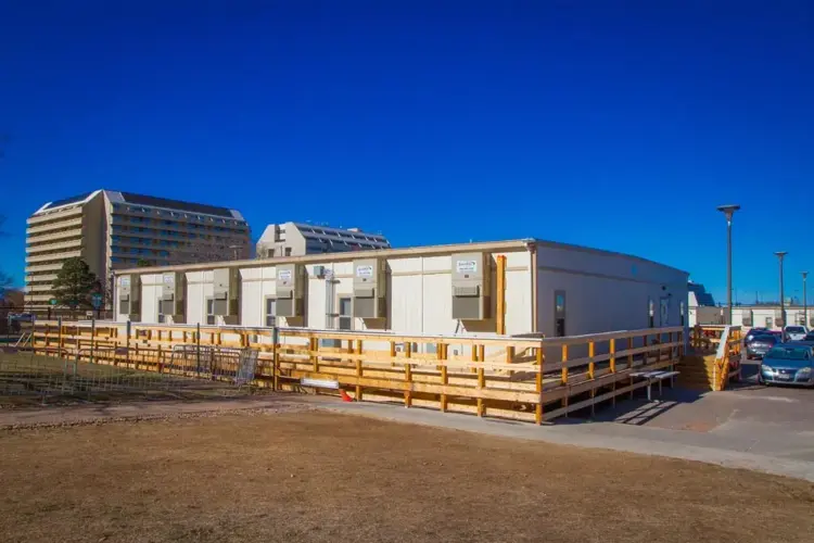 The Exterior of an S-Plex modular building with air conditioning in front of a cityscape or office buildings.