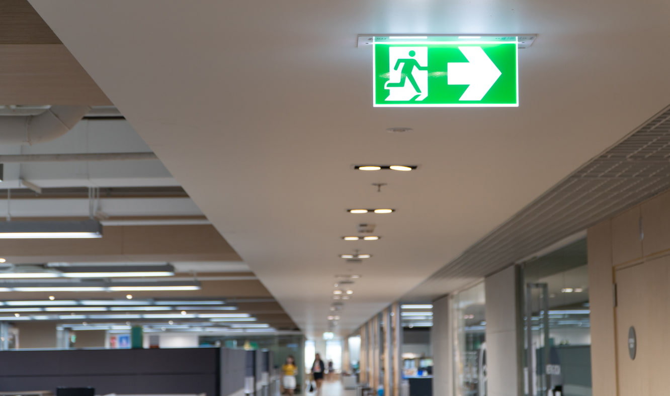 Clearly marked exits and hazard lights in an office space.