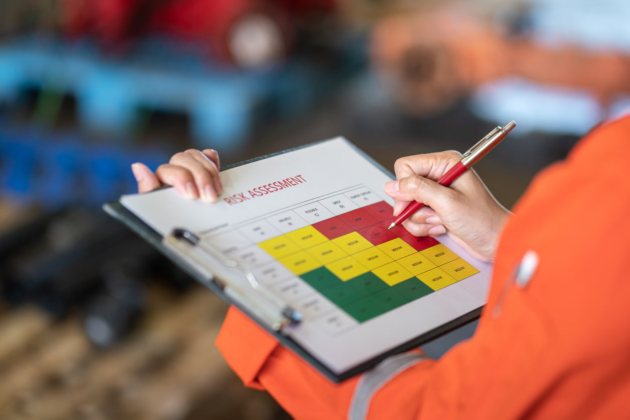 Person viewing and writing on a risk assessment document on a clipboard.