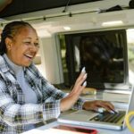 A happy woman having a video call for work in a mobile office trailer.