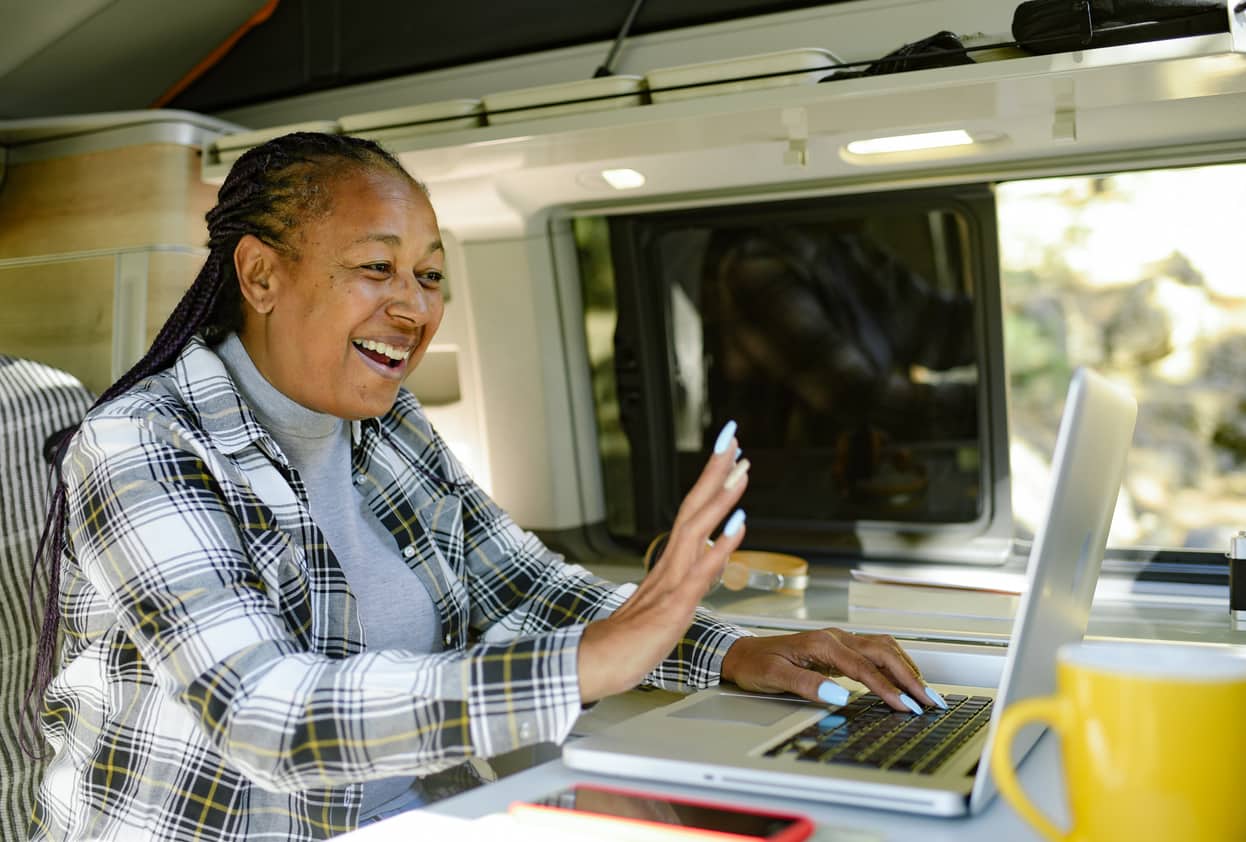 A happy woman having a video call for work in a mobile office trailer.