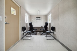 Interior view of a portable office container. Built-in desk with 2 office chairs and 2 side chairs