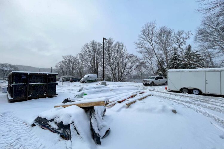 A snowy construction site with materials and equipment covered in snow.