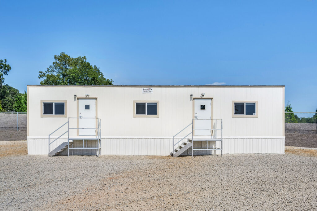 Front view of a 10x50 mobile office. Mobile office has skirting around front of building, 2 exterior doors shown, and steps leading up to the doors.