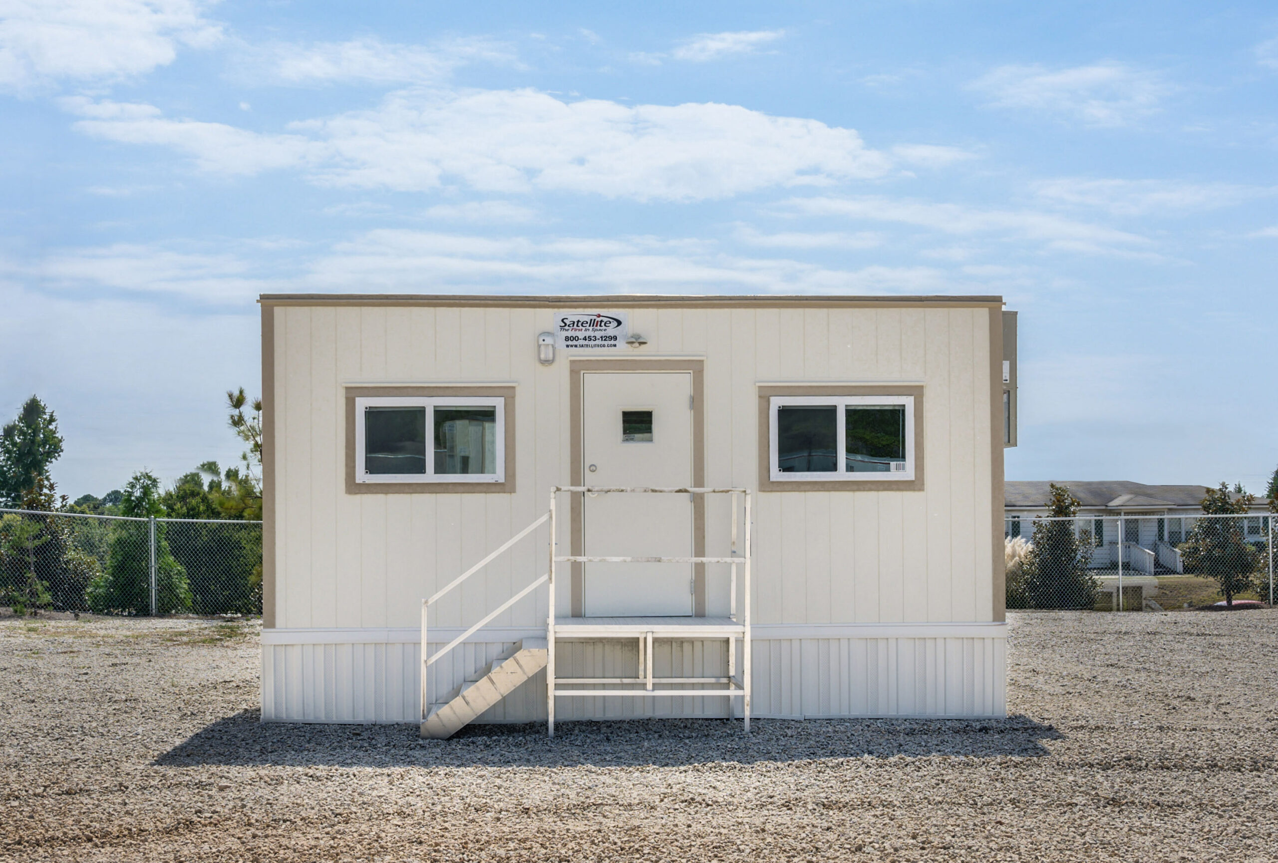 Front view of an 8x24 mobile office with steps leading up to a single door.