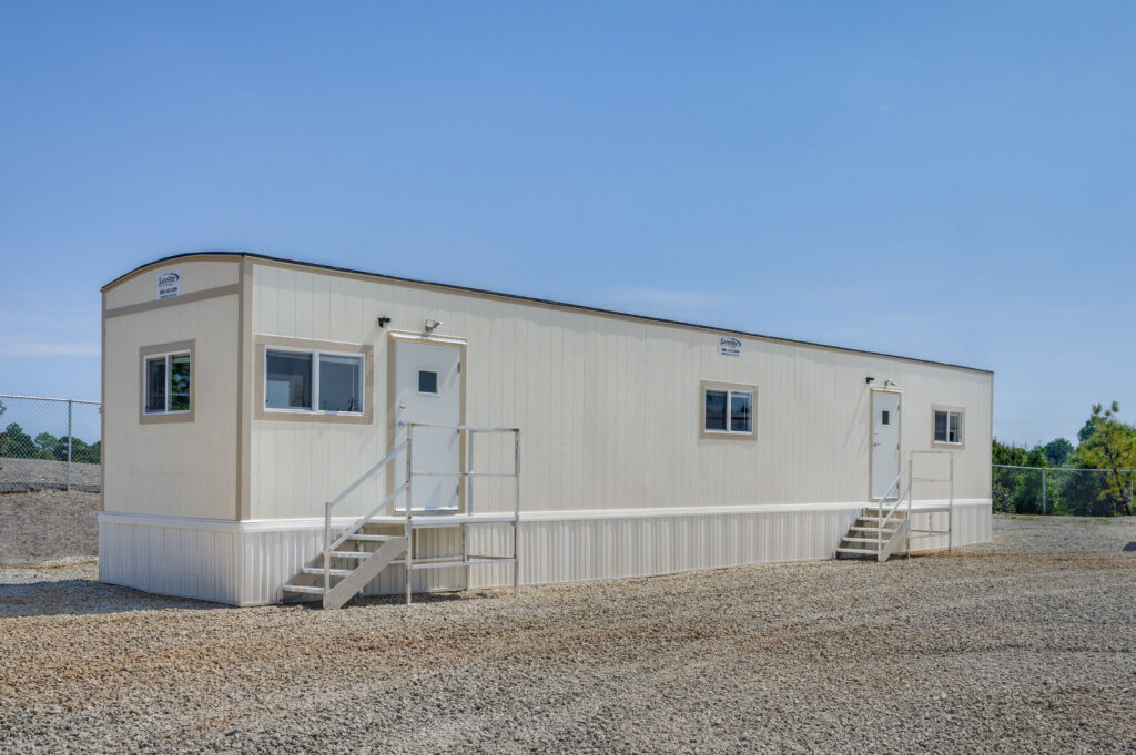 Side view of a 12x60 mobile office with skirting. 2 exterior doors with steps leading up to the doors.