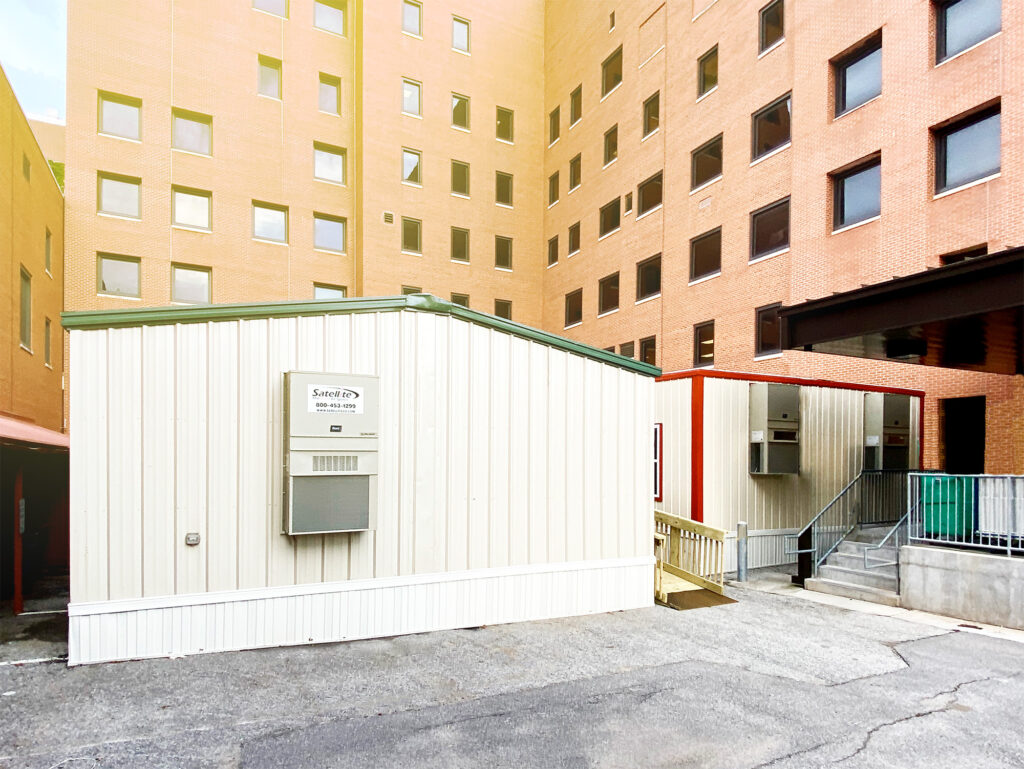A mobile medical building outside of a high rise hospital.
