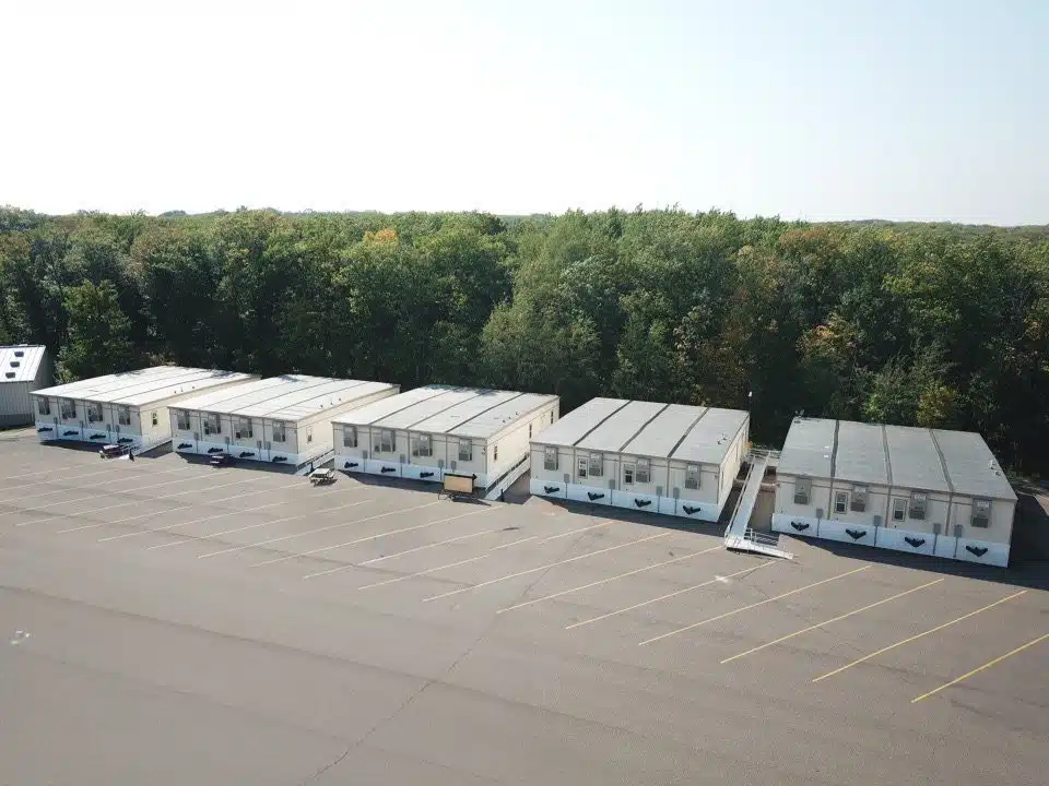5 4-plex modular buildings in a parking lot with ramps and steps leading to exterior doors.