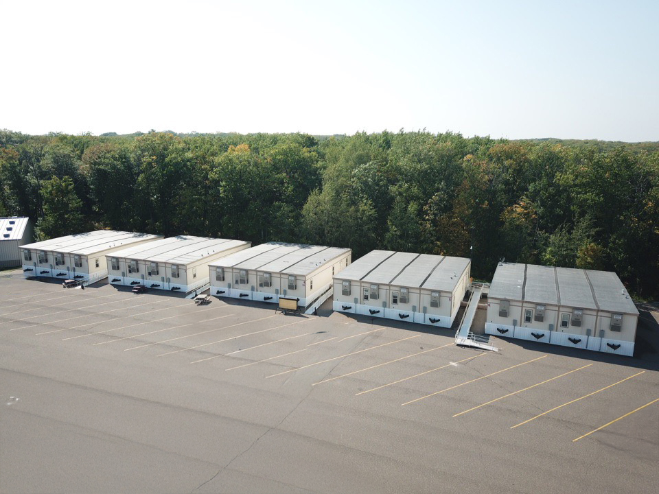A row of mobile offices on a concrete lot.
