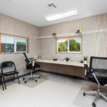 Interior Mobile Office with office furniture - 2 chairs at a desk with a folding chair against the wall