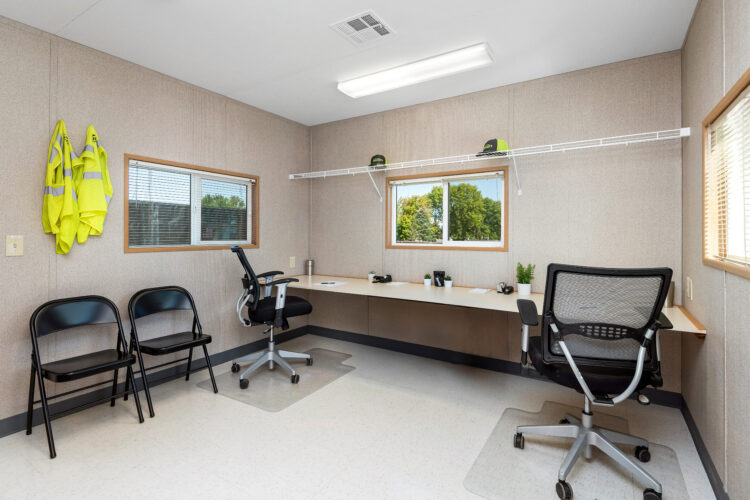 Interior Mobile Office with office furniture - 2 chairs at a desk with a folding chair against the wall