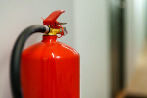 A red fire extinguisher with a safety pin, mounted indoors for emergency use.
