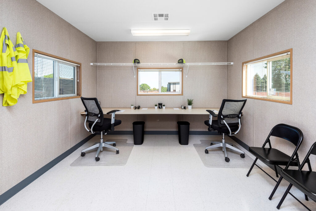 Construction site office with desk and chairs.