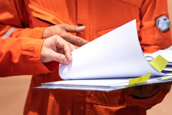 Close-up of a construction worker holding and reviewing printed documents.