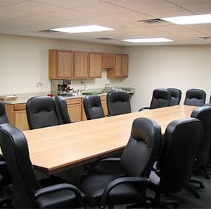 room with long table chair and kitchenette